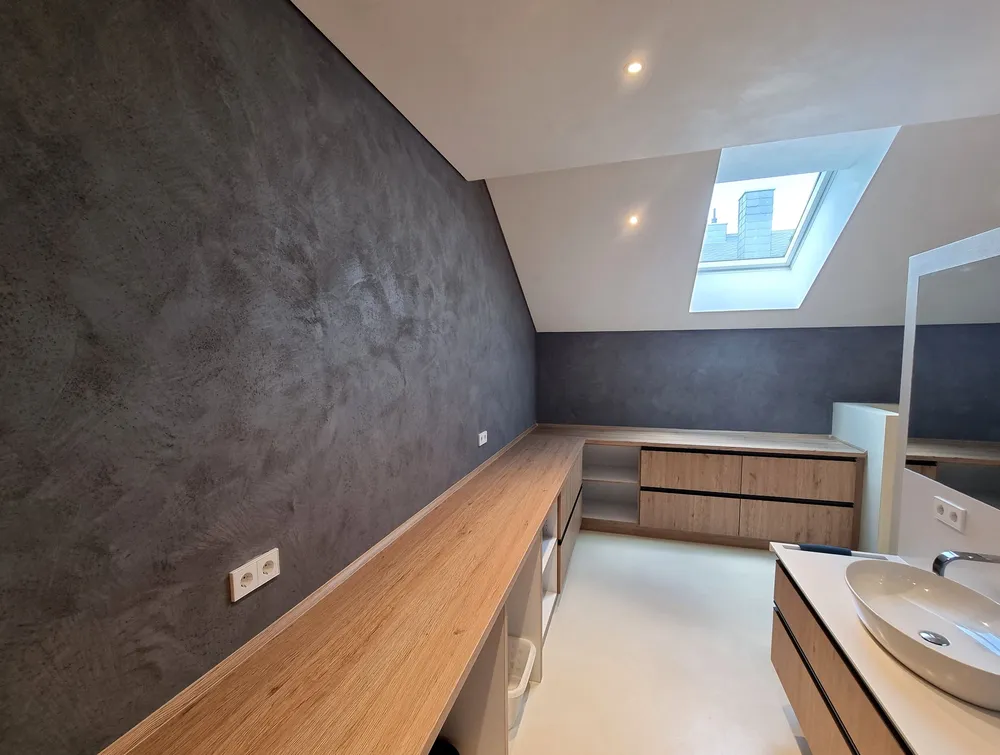 Raum mit dunkler Akzentwand, Holzmöbeln und Dachfenster